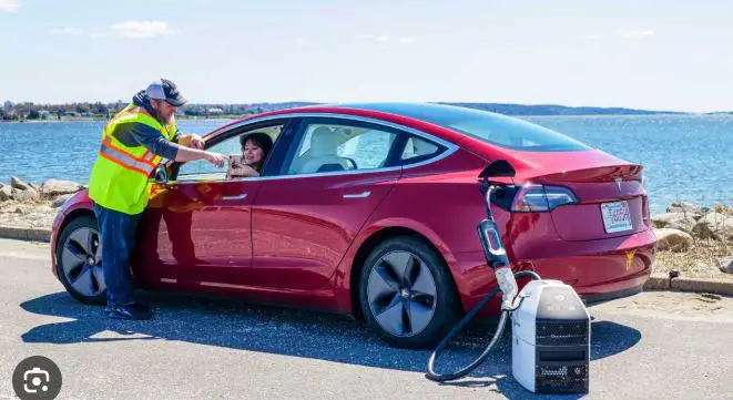 A WeCharge technician charging a red electric car beside the water